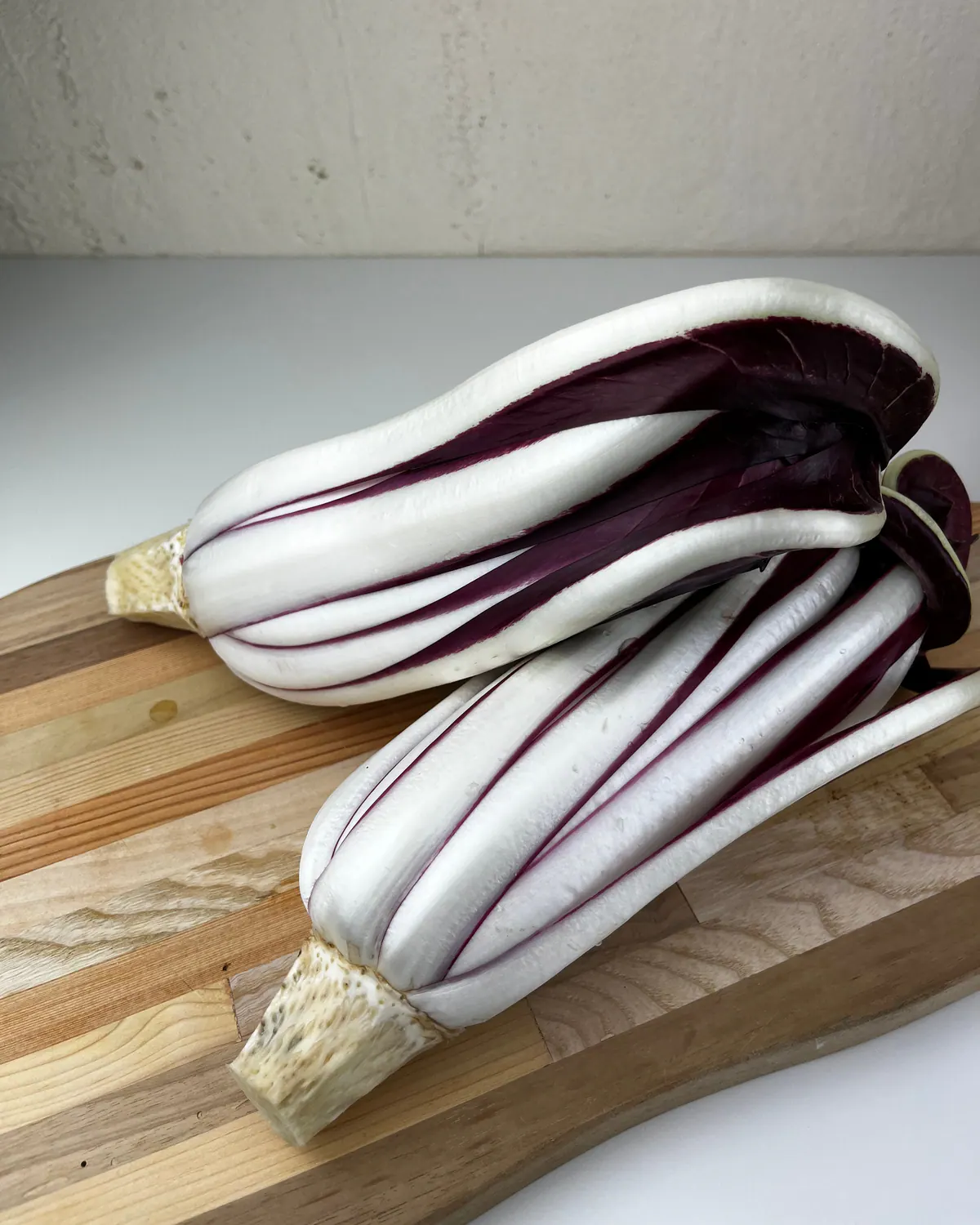 Due cespi di Radicchio Tardivo su un tagliere di legno